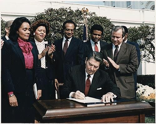 In 1983, after years of fighting, Coretta Scott King (left) was successful in getting her late husband's birthday recognized as a national holiday. Here, President Ronald Reagan signs the legislation. (File photo)