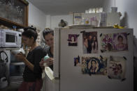Photos of family members who migrated to the U.S. cover the fridge in the home of sisters Melanie and Merlyn Rolo Gonzalez, in Havana, Cuba, Saturday, Dec. 10, 2022. Days later, they themselves made the journey. The sisters sold a house left to them by their father, along with the refrigerator, television and anything else of value in exchange for American dollars to help pay for the journey. (AP Photo/Ramon Espinosa)