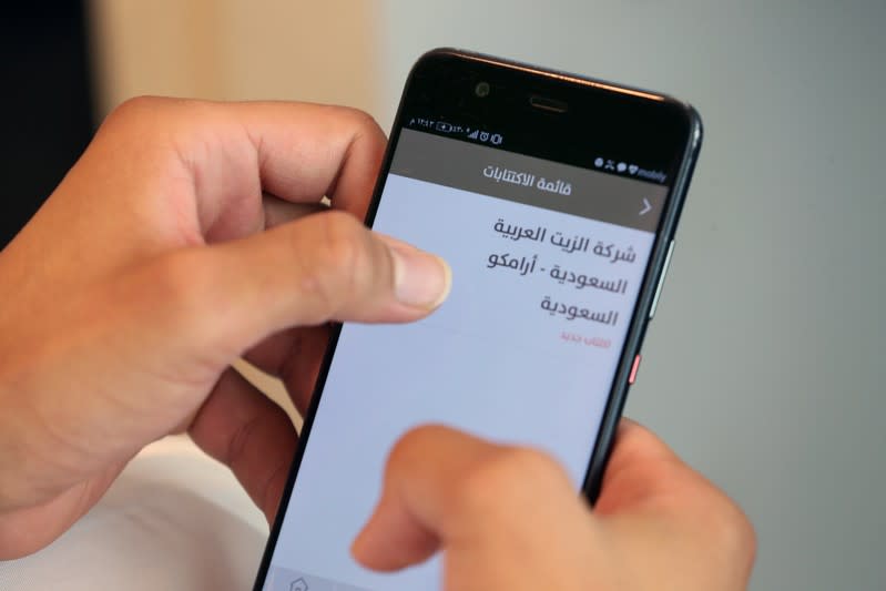 A Saudi man checks his mobile phone following the start of Aramco IPO, in Riyadh