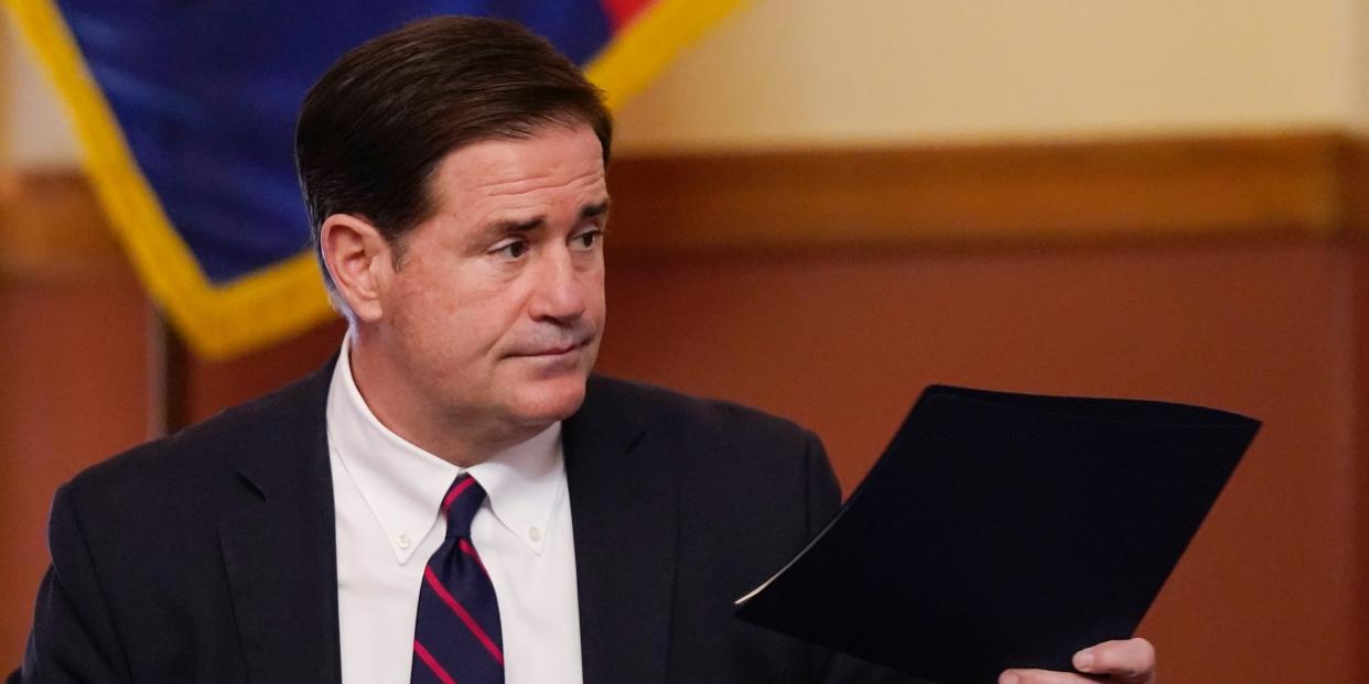 In this Nov. 30, 2020 file photo, Arizona Gov. Doug Ducey hands over his signed election documents to certify the election results for federal, statewide, and legislative offices and statewide ballot measures at the official canvass at the Arizona Capitol in Phoenix