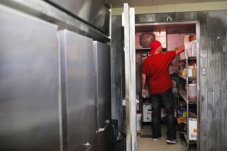 William Luz, who was recently released from the Barnstable County House of Corrections, retrieves ingredients from the walk-in freezer at the restaurant where he is a cook in Sandwich, Massachusetts August 29, 2014. REUTERS/Brian Snyder