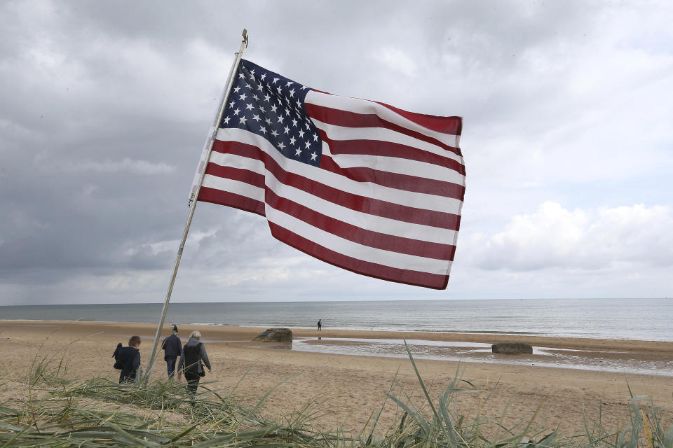 People walk on Omaha beach, Normandy, where an American is planted, Wednesday June 5, 2019. Extensive commemorations are being held in the U.K. and France to honor the nearly 160,000 troops from Britain, the United States, Canada and other nations who landed in Normandy on June 6, 1944 in history's biggest amphibious invasion. (AP Photo/David Vincent)