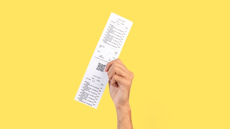 Hand holding receipt yellow background