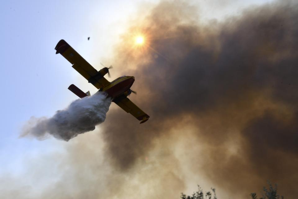 An aircraft drops water during a wildfire near Olympia town, western Greece, Thursday, Aug. 5, 2021. Wildfires rekindled outside Athens and forced more evacuations around southern Greece Thursday as weather conditions worsened and firefighters in a round-the-clock battle stopped the flames just outside the birthplace of the ancient Olympics. (Giannis Spyrounis/ilialive.gr via AP)