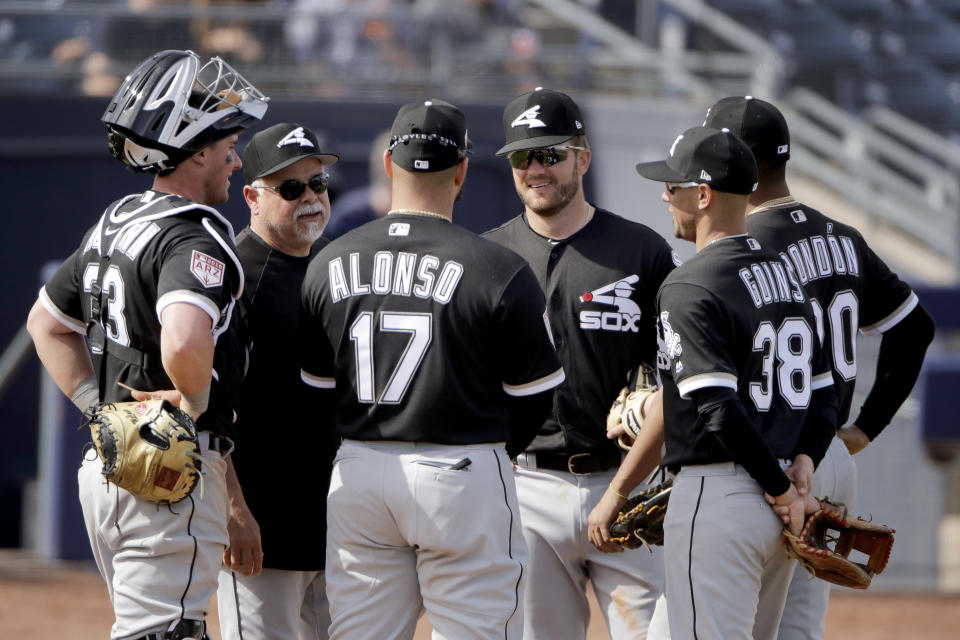Chicago White Sox manager Rick Renteria, second from left, talks to his players as he makes a pitching change during the fourth inning of a spring training baseball game against the San Diego Padres, Sunday, Feb. 24, 2019, in Peoria, Ariz. (AP Photo/Charlie Riedel)
