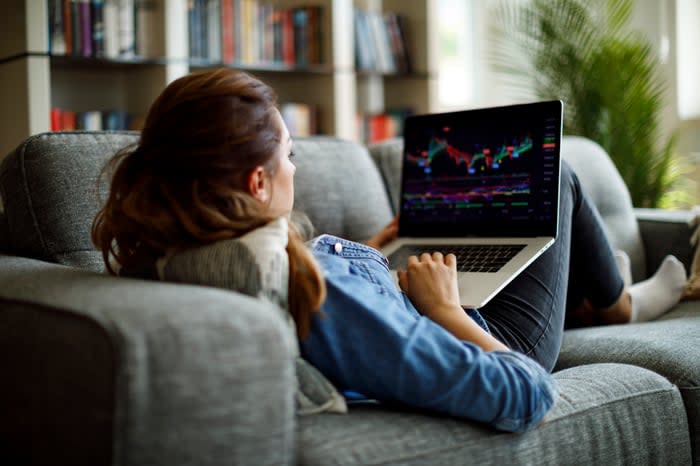 A person on a couch looking at a chart on a laptop.