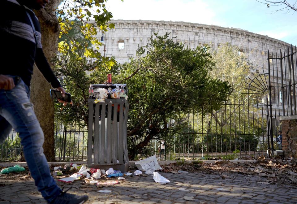 A man walks past a bin overflowing with uncollected trash at Colle Oppio park facing the ancient Colosseum, in Rome, Monday, Nov. 12, 2018. Rome’s monumental problems of garbage and decay exist side-by-side with Eternal City’s glories. (AP Photo/Andrew Medichini)