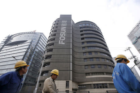 Construction workers walk past a building of the headquarters of Fosun International, in Shanghai, China, December 14, 2015. RETUERS/Aly Song/File Photo