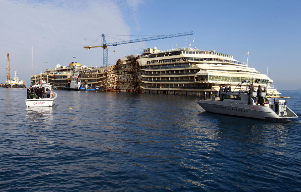 A wreath, seen at center-left, floats in the water near the shipwrecked Costa Concordia off the coast of the Tuscan Island of Giglio, Italy, Monday, Jan. 13, 2014. Survivors of the capsized Costa Concordia are commemorating the second anniversary of the grounding off Tuscany that killed 32 people with a candlelight march on the island later on and a moment of silence in the Italian courtroom where the captain is on trial. (AP Photo/Gregorio Borgia)