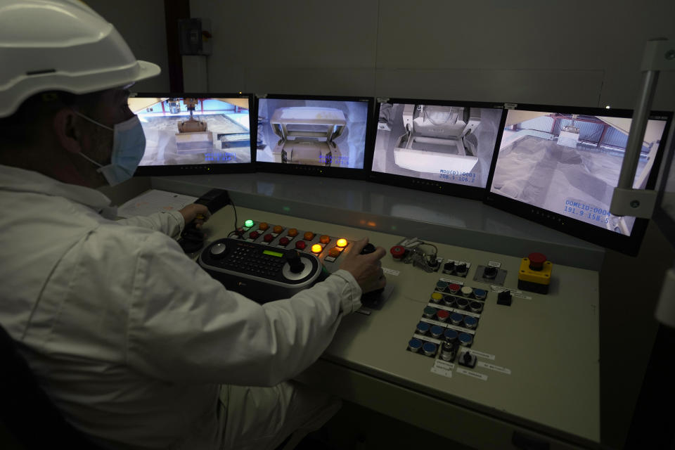 A technician pilots robots for radioactive waste storage in a concrete-sealed warehouse in the Aube region of eastern France in Soulaines-Dhuys, Friday, Oct. 29, 2021. The site holds low- to mid-level radioactive waste from French nuclear plants as well as research and medical facilities, and its concrete-sealed warehouses are designed to store the waste for at least 300 years. (AP Photo/Francois Mori)