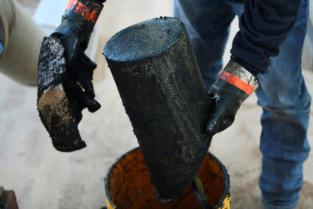 Carlos Riojas cleans out a filter at a wastewater injection facility operated by On Point Energy in Big Spring, Texas U.S. February 12, 2019. Picture taken February 12, 2019. REUTERS/Nick Oxford