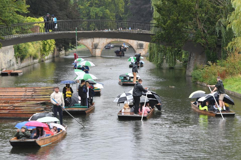 People punt in the rain along the River Cam in Cambridge (PA)