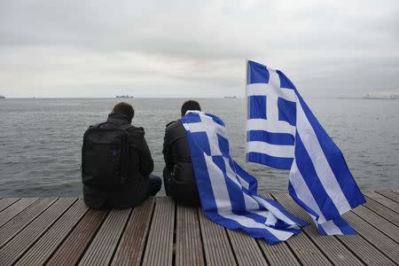 Two protesters, one of them wearing a Greek national flag, rest on the seaside promenade during a rally against the use of the term "Macedonia" in any solution to a dispute between Athens and Skopje over the former Yugoslav republic's name, in the northern city of Thessaloniki, Greece, January 21, 2018. REUTERS/Alexandros Avramidis