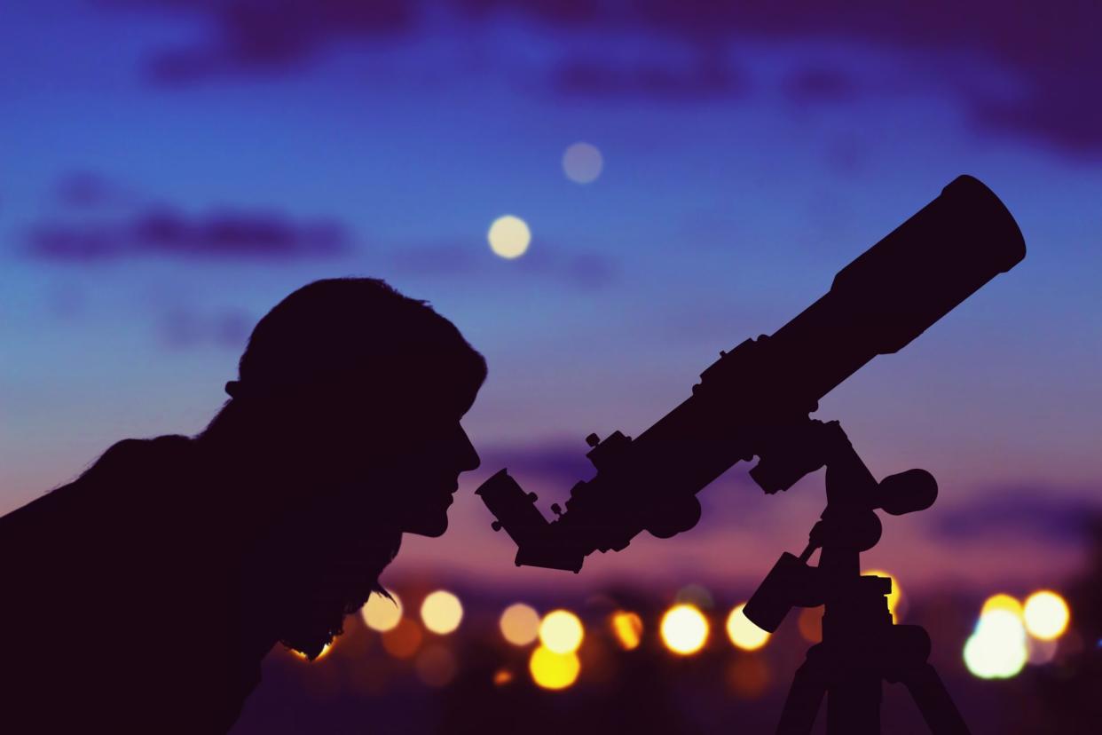 woman looking through telescope