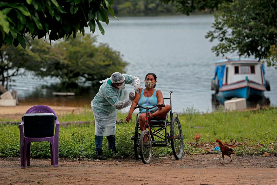 A health worker from the Ministry of Health Department for Indigenous Health adminsters a second doses of a COVID-19 vaccine to a woman in the village Esperanca do Rio Arapiun, in the Lower Amazon region of the state of Para, near Santarem in Brazil, on Feb. 14. (Photo: TARSO SARRAF/AFP/Getty Images)