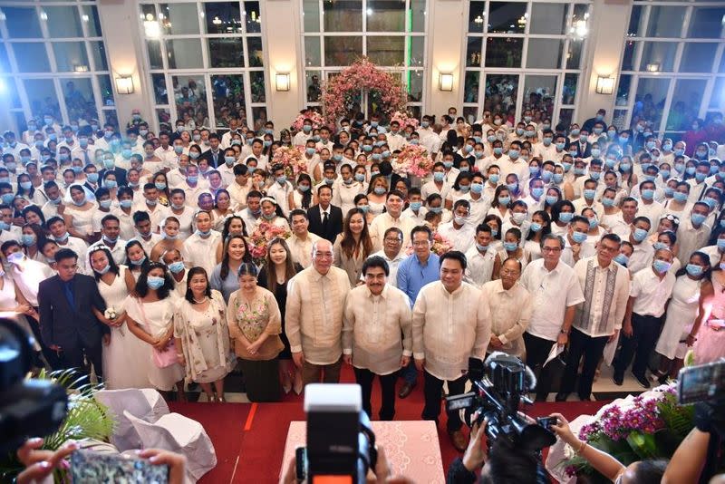 Filipino couples kiss while wearing their face masks in a government-sponsored mass wedding in Bacolod City