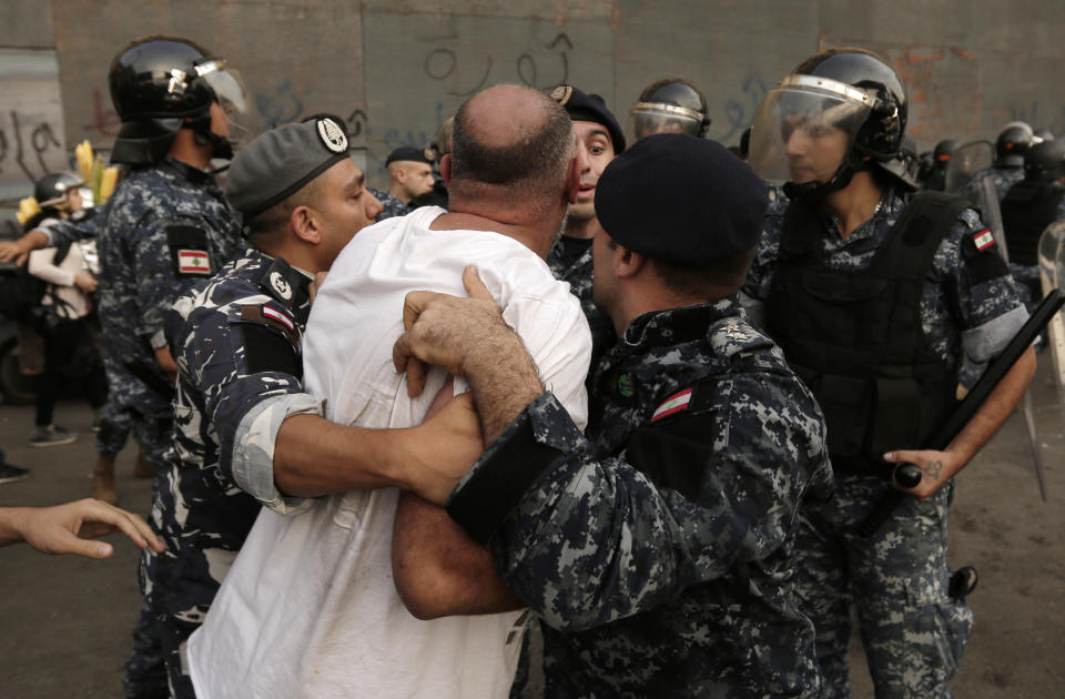 Lebanese riot policemen arrest a Hezbollah supporter after a clashes erupted between anti-government protesters and Hezbollah supporters during a protest in Beirut, Lebanon, Friday, Oct. 25, 2019. Leader of Lebanon's Hezbollah calls on his supporters to leave the protests to avoid friction and seek dialogue instead. (AP Photo/Hassan Ammar)