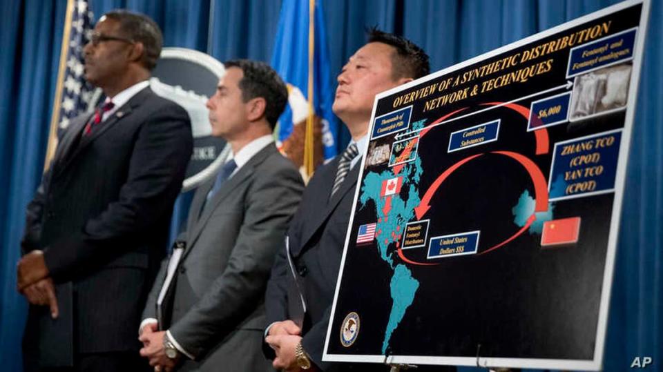 Law enforcement officials appear before a drug distribution poster during a news conference at the Justice Department in Washington on Oct. 17, 2017, to announce the indictments of two Chinese fentanyl traffickers in the fight to keep opiate substances from entering the United States.