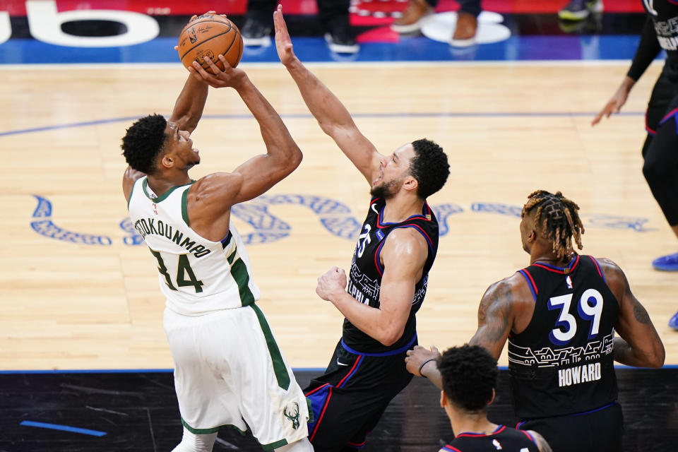 Milwaukee Bucks' Giannis Antetokounmpo , left, goes up for a shot against Philadelphia 76ers' Ben Simmons during the second half of an NBA basketball game, Wednesday, March 17, 2021, in Philadelphia. (AP Photo/Matt Slocum)