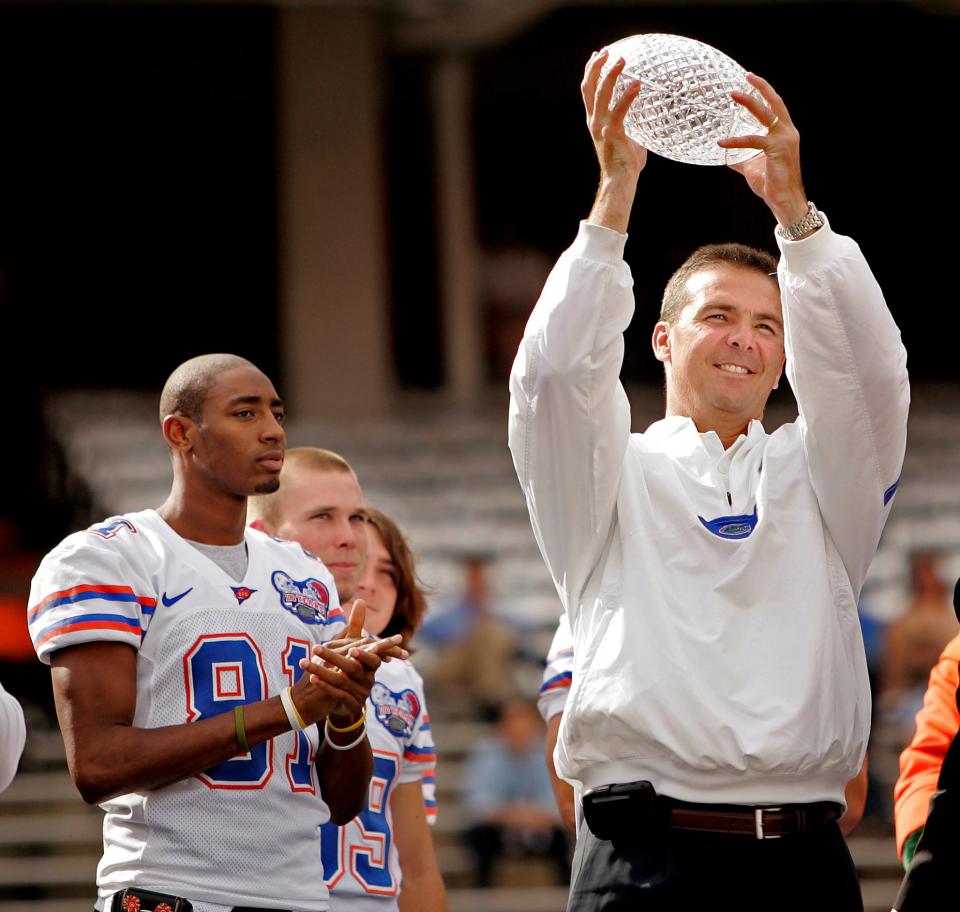 Florida head coach Urban Meyer holds up the BCS National Championship Trophy, Saturday, Jan. 13, 2007 during the celebration at Ben Hill Griffin Stadium. At left are players Dallas Baker, Chris Hetland and Eric Nappy. (TRACY WILCOX/The Gainesville Sun)