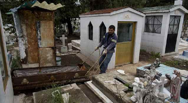 A coffin containing human remains is hauled away after being exhumed to free up space for new burials at the cemetery. Photo: AP