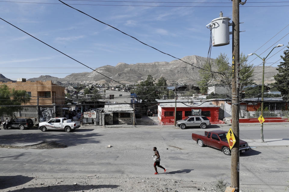 In this July 31, 2019, photo, Alphat, of Uganda, runs through a neighborhood surrounding the El Buen Pastor shelter for migrants in Cuidad Juarez, Mexico. Alphat runs relentlessly, and seemingly effortlessly. People stop to stare, surprised to see a black man with ham-sized biceps and impossibly broad shoulders running through this city, which has long been a magnet for migrants. (AP Photo/Gregory Bull)