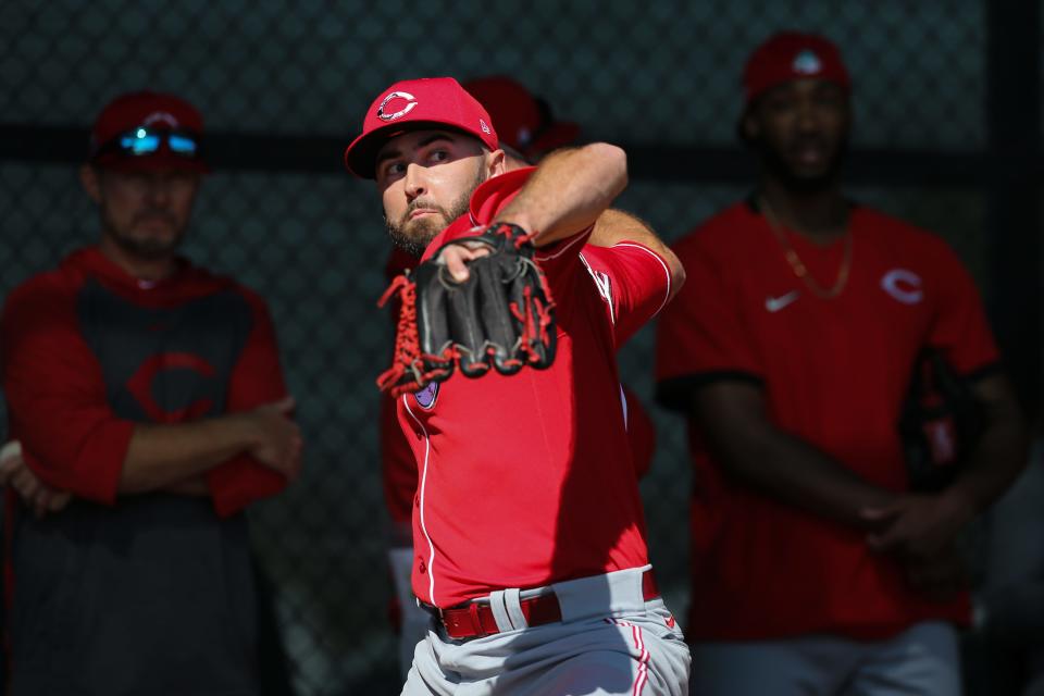 Seth Etherton, left background, watches Cincinnati Reds relief pitcher Ryan Hendrix (73) deliver a pitch during spring practice, Sunday, Feb. 16, 2020, at the Cincinnati Reds Spring Training Facility in Goodyear, Arizona.
