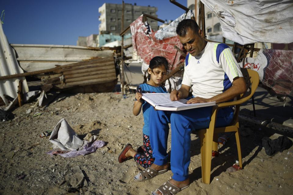 A Palestinian man reads a copy of the Koran, Islam's holiest book, with a young girl outside his home at Al-Shati camp in Gaza City on June 6.