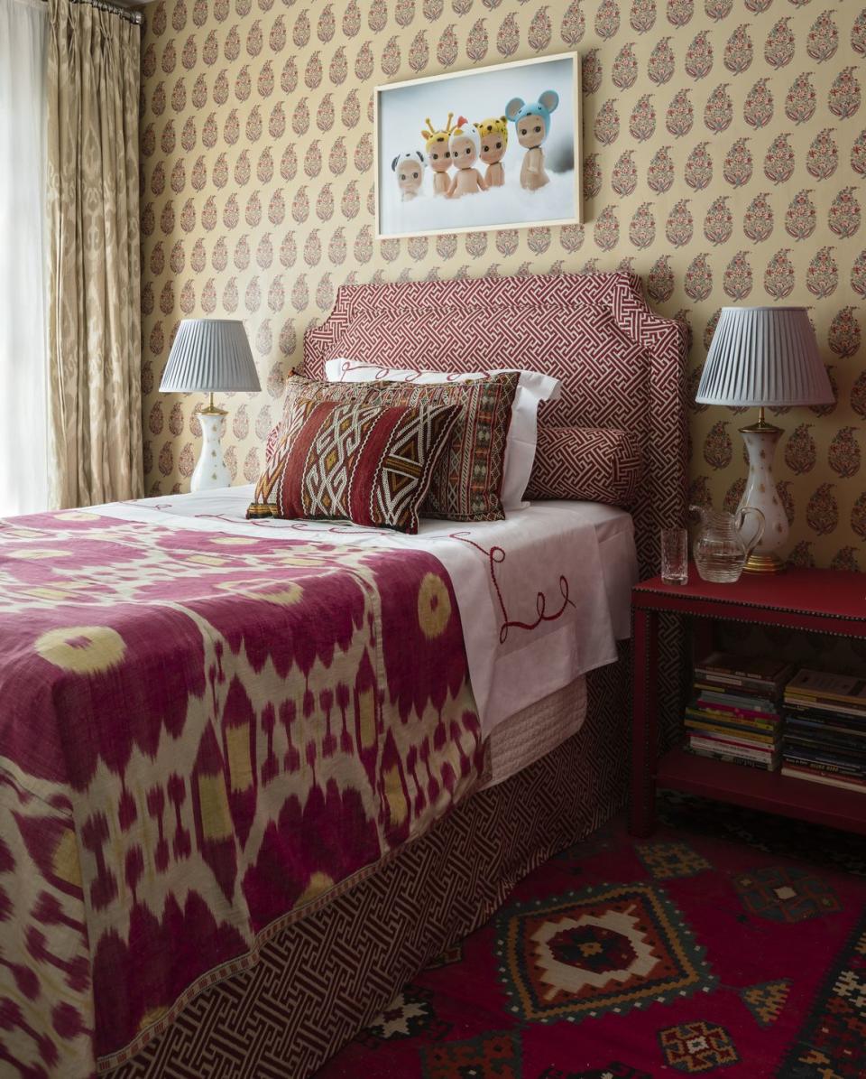 a brightly patterned bedroom with paisley wallpaper and bed with pink textile coverlet