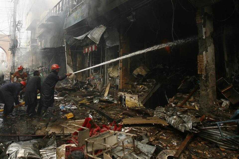 Firefighters work to extinguish a fire from a building at the site of a bomb attack in Peshawar