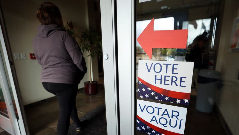 A woman walks past “Vote Here” signs at Taylorsville City Hall on Election Day in Taylorsville on Tuesday, Nov. 8, 2022.