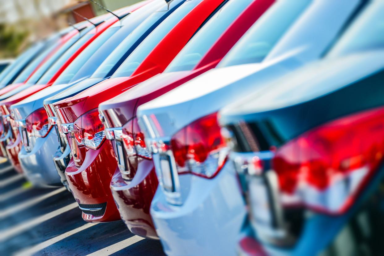 Row of new cars for sale at car dealership.