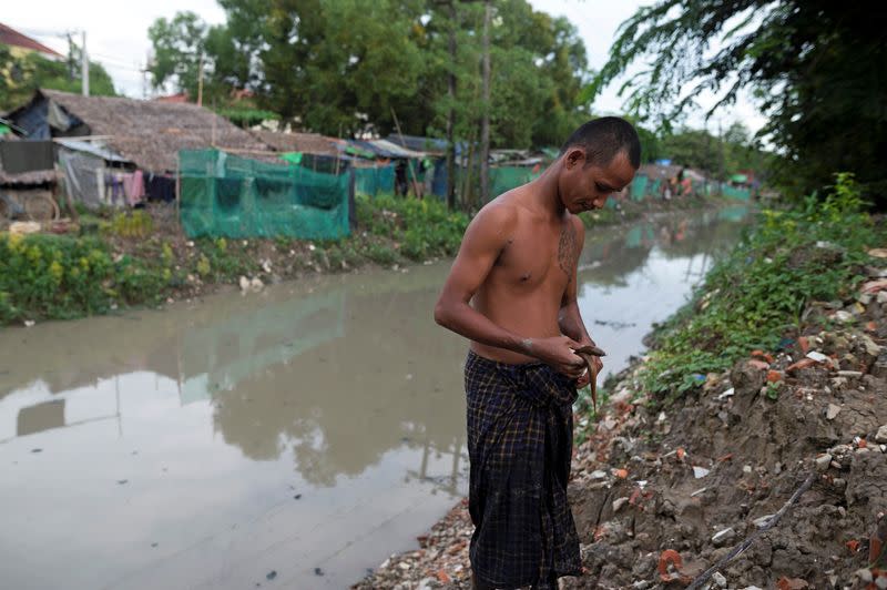 Man catches eel from open drain beside slum in Yangon during coronavirus lockdown