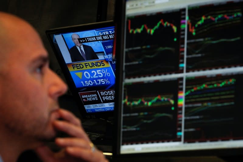 A screen displays the U.S. Federal Reserve interest rates announcement as traders work on the floor of the NYSE in New York