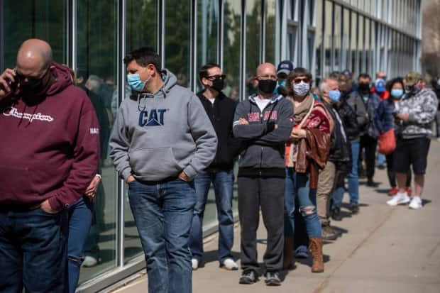 People line up outside an immunization clinic to get their Oxford-AstraZeneca COVID-19 vaccine in Edmonton on April 20, 2021.