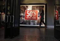 A woman walks by a discount sign at an Abercrombie & Fitch store at a shopping mall in Garden City, New York November 28, 2014. REUTERS/Shannon Stapleton