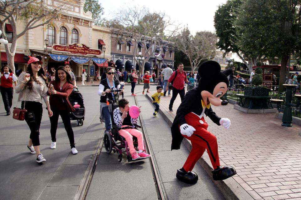 Visitors follow Mickey Mouse for photos at Disneyland in Anaheim, California.