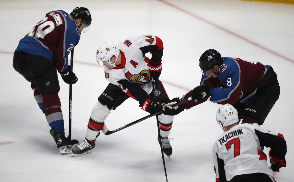 Ottawa Senators center Jean-Gabriel Pageau, center, fights for control of the puck with Colorado Avalanche center Nathan MacKinnon, left, and defenseman Cale Makar in the first period of an NHL hockey game Tuesday, Feb. 11, 2020, in Denver. (AP Photo/David Zalubowski)