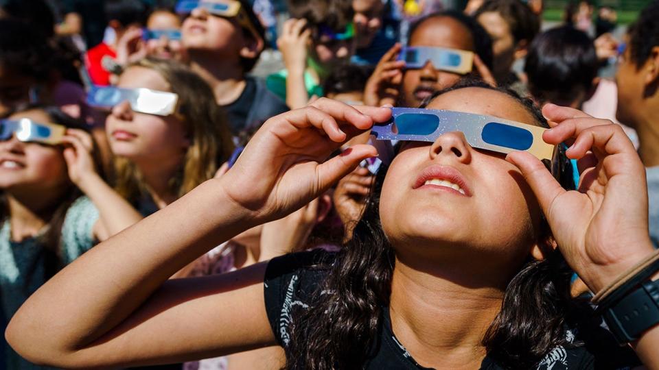 FILE -- Pupils, wearing protective glasses, look at the partial solar eclipse in Schiedam on June 10, 2021.