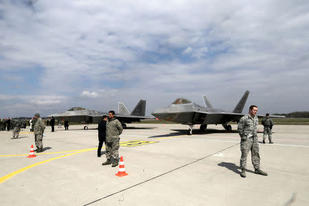 U.S. Army soldiers guard as U.S. Air Force F-22 Raptor fighters are parked in the military air base in Siauliai, Lithuania, April 27, 2016. REUTERS/Ints Kalnins