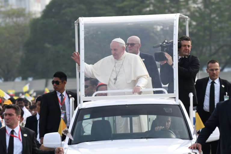 Pope Francis (C) smiled and waved as he snaked through the estimated 200,000 faithful in his "popemobile", many of the worshippers holding Myanmar flags and wearing colourful clothes from the country's myriad ethnic groups