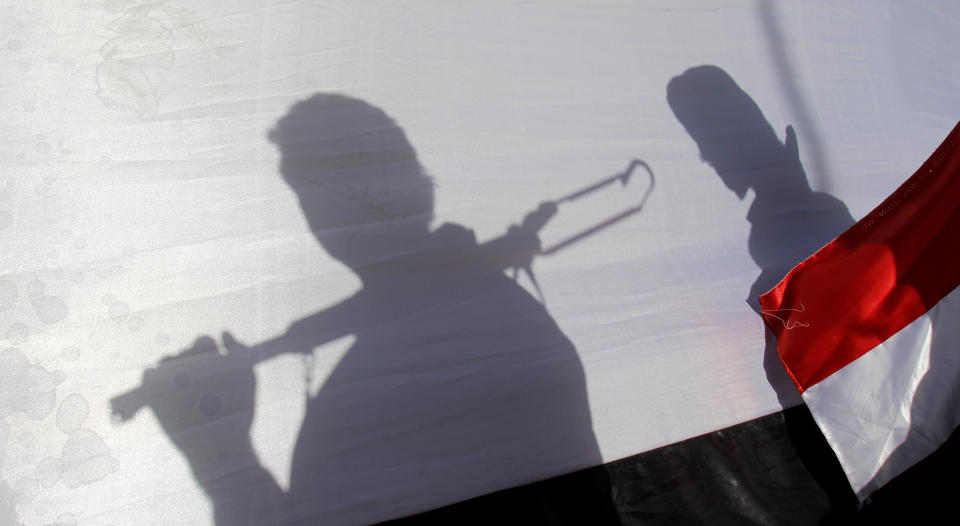 FILE - The shadow of Shiite rebels, known as Houthis, are cast on a large representation of the Yemeni flag as they attend a demonstration against an arms embargo imposed by the U.N. Security Council on Houthi leaders, in Sanaa, Yemen, Thursday, April 16, 2015. On Friday, Nov. 3, 2023, The Associated Press reported on stories circulating online incorrectly claiming Yemen has declared war against Israel. (AP Photo/Hani Mohammed, File)