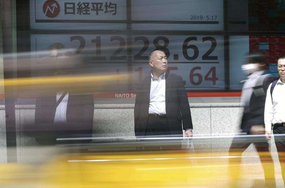 People walk past an electronic stock board showing Japan's Nikkei 225 index at a securities firm in Tokyo Friday, May 17, 2019. Asian stocks were mixed on Friday amid worries that U.S. economic sanctions on Huawei would put a drag on trade negotiations with China. (AP Photo/Eugene Hoshiko)