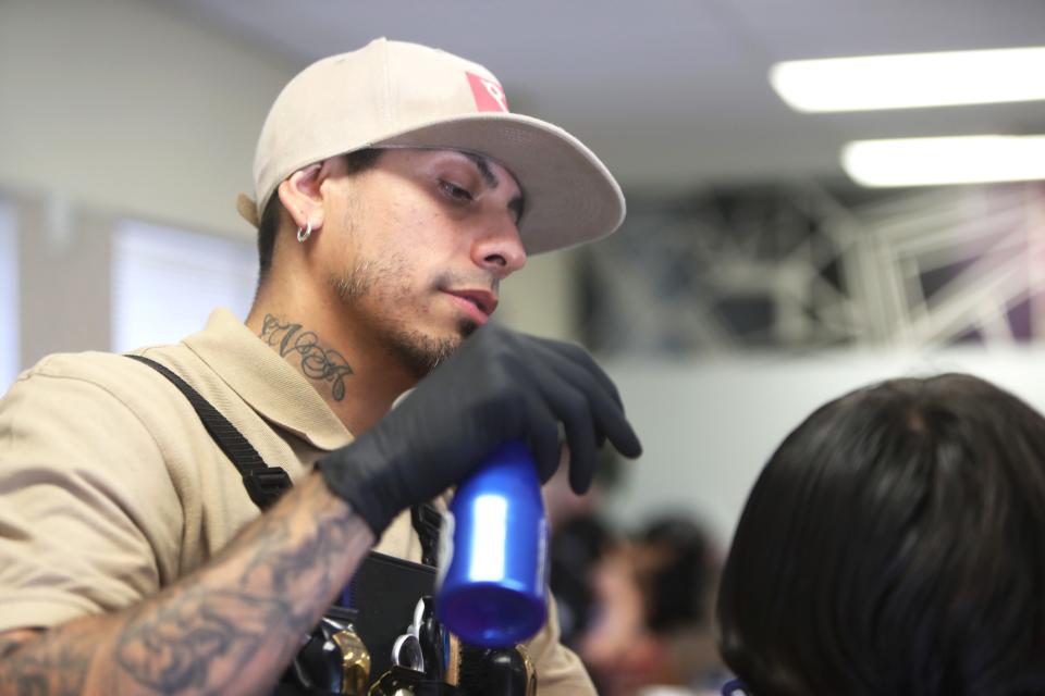 David Rodriguez of ClipDart cuts Angel Lopez's hair in Glendale on Saturday, July 22, 2023.