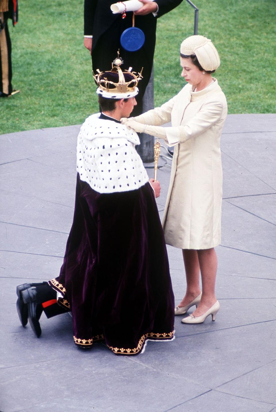 Queen Elizabeth II adjusting the robe of Prince Charles during his investiture as the Prince of Wales at Caernarfon Castle (PA) (PA Wire)