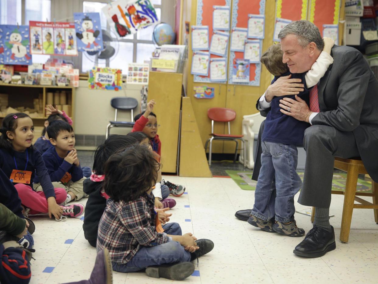 New York City Mayor Bill de Blasio hugs a child after reading a book to a prekindergarten class (AP)