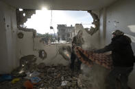 Palestinians collect their belongings from their damaged house after an Israeli airstrike in Rafah, southern Gaza Strip, Saturday, Jan. 27, 2024. (AP Photo/Fatima Shbair)