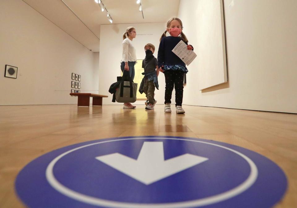 An arrow on the floor directs visitors Alexandra Megan, from left, son Graydon, 5, and daughter Madeline, 3, at the Milwaukee Art Museum on Saturday.