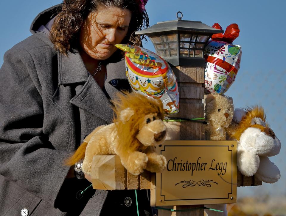 Danni Legg lowers her head Jan. 16, 2014, while next to her son's, Christopher, wooden cross that stands outside the Plaza Towers Elementary School during a balloon release to mark what would have been Christopher's 10th birthday in Moore.