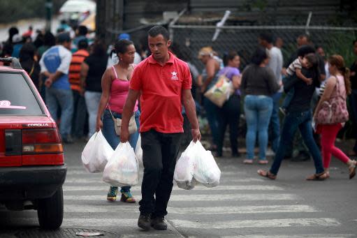 Venezolanos hacen fila en la puerta de un supermercado en Caracas, el 2 de abril de 2014 (AFP | Federico Parra)